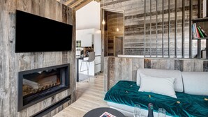 Een moderne woonkamer met een open haard, een bank, een televisie en een keukenhoek.