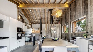 Een moderne keuken met een houten eettafel, witte kasten en een hangende lamp.