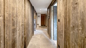 Een gang met houten wanden en een betegelde vloer, die leidt naar een kamer met een deur.