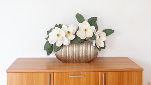A wooden cabinet with a vase of white flowers and a framed floral painting on the wall. - Holiday Home 'Limpiddu 4' with Mountain View, Shared Garden and Balcony (Limpiddu)