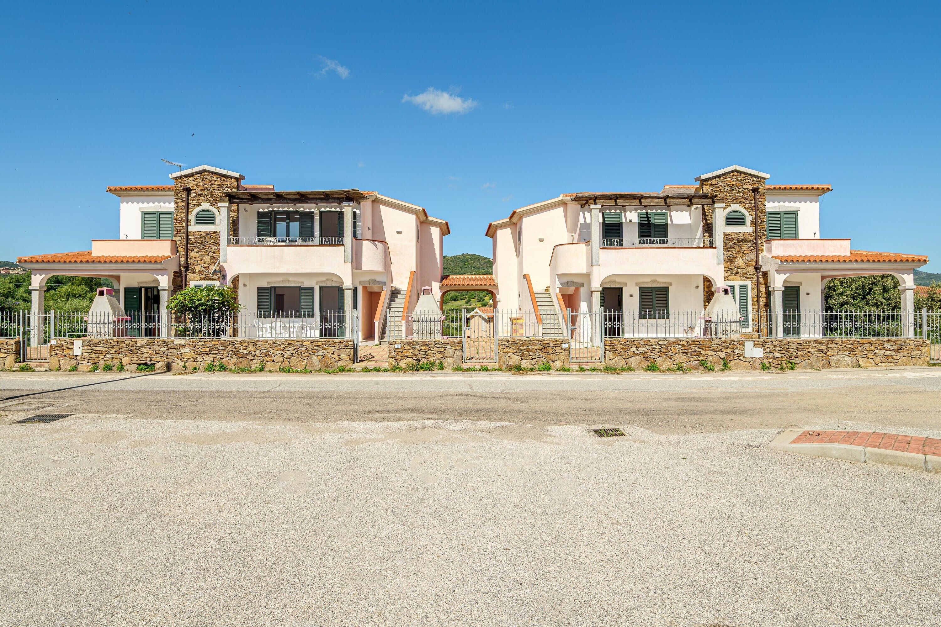 A symmetrical, two-story building with a stone facade, multiple balconies, and a clear sky.