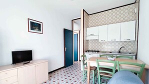 En kompakt bolig med tekøkken, spiseplads og fjernsyn på en kommode.