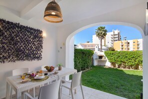 A dining area with a table set for breakfast, a decorative wall, and a view of the surrounding buildings and greenery.