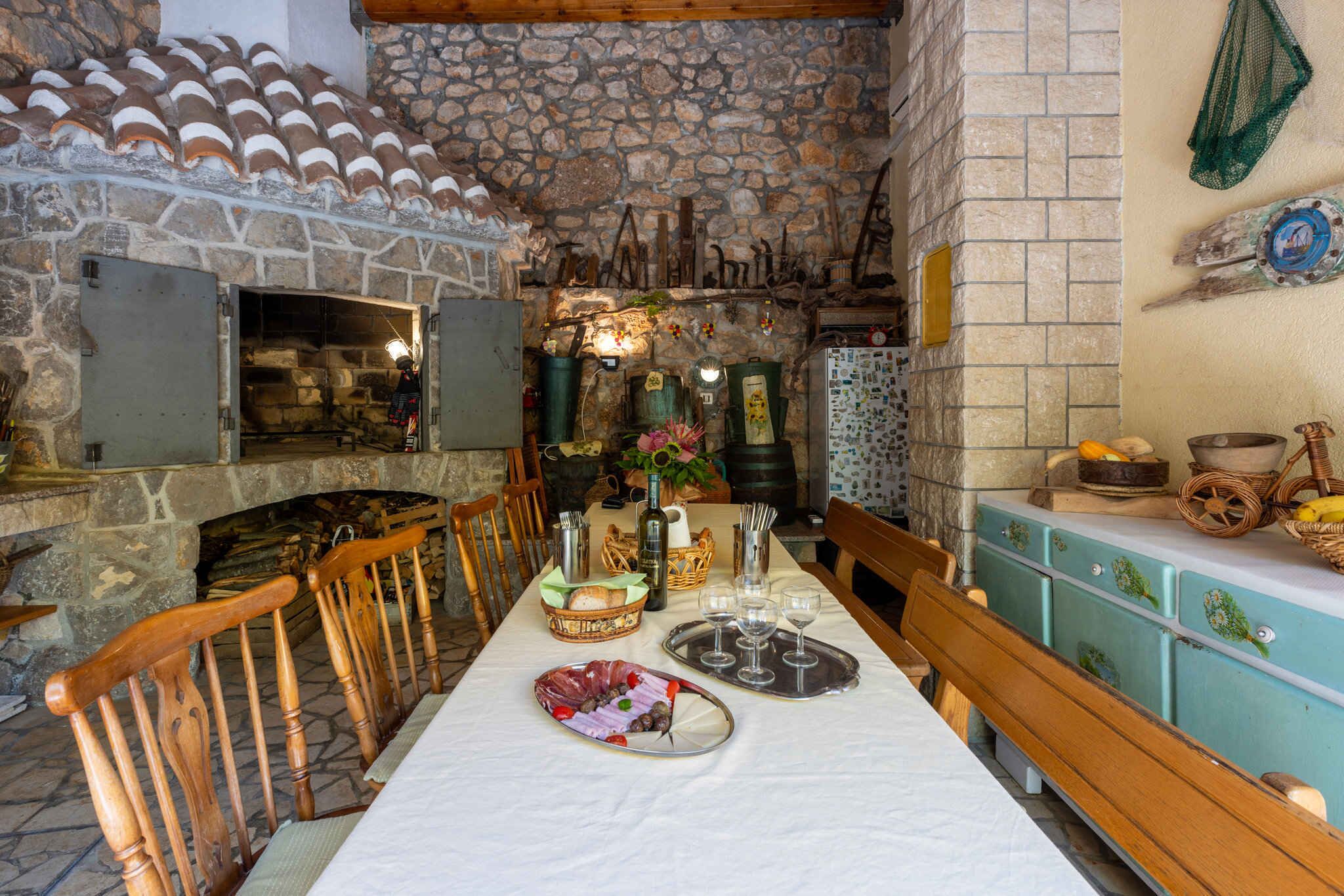 Un espace de restauration aux murs de pierre, avec une longue table dressée pour un repas, des chaises en bois et une atmosphère rustique.