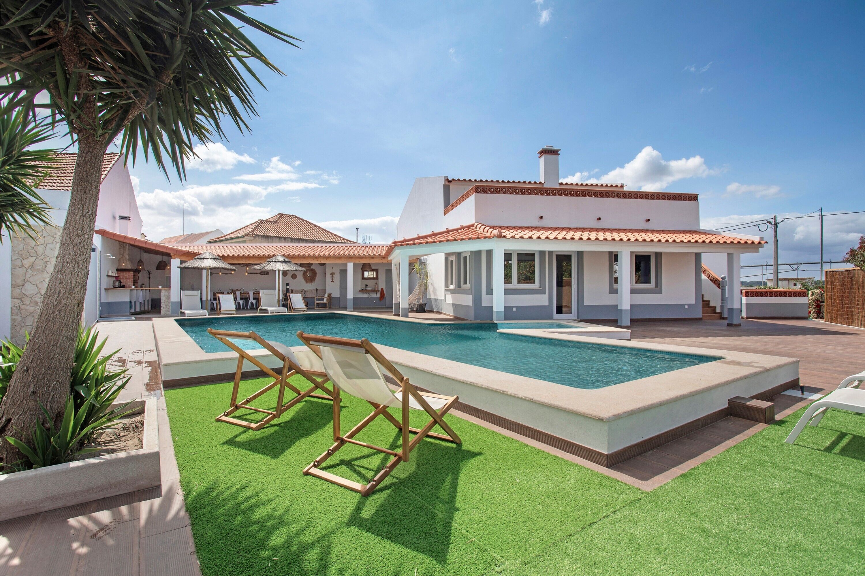 Ein modernes Haus mit Pool, Sitzgelegenheit im Freien und einem gepflegten Garten.
