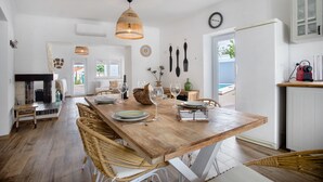 A spacious dining area with a wooden table, wicker chairs, and a hanging light fixture. - Holiday Home 'Vila River Sublime' with Private Pool, Wi-Fi and Air Conditioning (Valada)