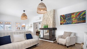A living room with a sofa, armchair, fireplace, and artwork. - Holiday Home 'Vila River Sublime' with Private Pool, Wi-Fi and Air Conditioning (Valada)