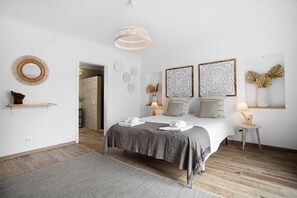 Een slaapkamer met een bed, bedlampen, een spiegel en decoratieve muurkunst.