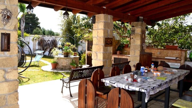 An outdoor patio with a stone table, chairs, and a grill area. - Villa 'Ll04 Hikari with Outdoor Spaces', Private Garden, Wi-Fi & Air Conditioning (San foca)