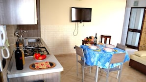A kitchen with a gas stove, a sink, and a dining area with a table set for four. - Villa 'Ll04 Hikari with Outdoor Spaces', Private Garden, Wi-Fi & Air Conditioning (San foca)