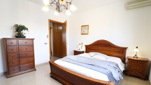 Une chambre à coucher avec un lit en bois, une commode, une table de chevet, une lampe et une plante en pot.