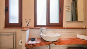 Une salle de bain avec une grande fenêtre, un lavabo sur colonne, une serviette et un miroir.