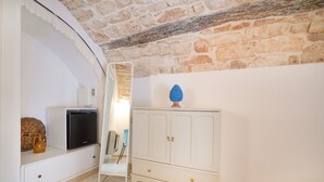 Une pièce comprenant un meuble blanc, un téléviseur, un panier en osier et un objet décoratif bleu posé sur le dessus du meuble.