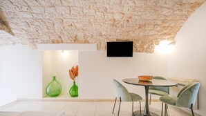 Un espace repas doté d’un plafond en pierre, d’un téléviseur à écran plat fixé au mur et d’une table avec des chaises.