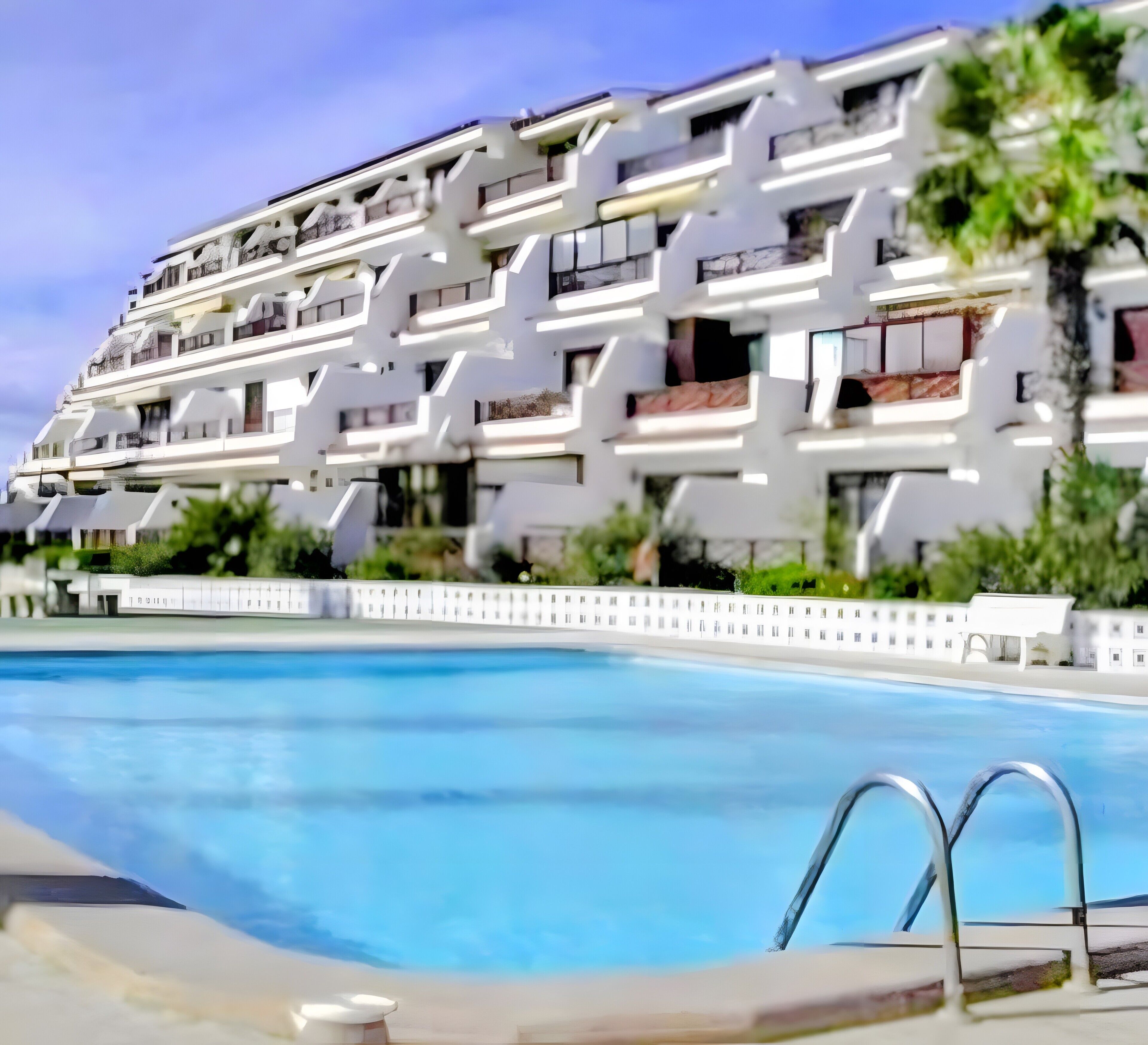 A multi-story hotel with a swimming pool in the foreground.