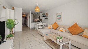 A modern living room with a sofa, coffee table, and a dining area with chairs and a table. - Apartment with Stunning Ocean View, Pool, Garden, Terrace & Wi-Fi (Costa del Silencio)