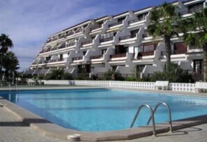 Un hotel de varios pisos con una piscina al frente.