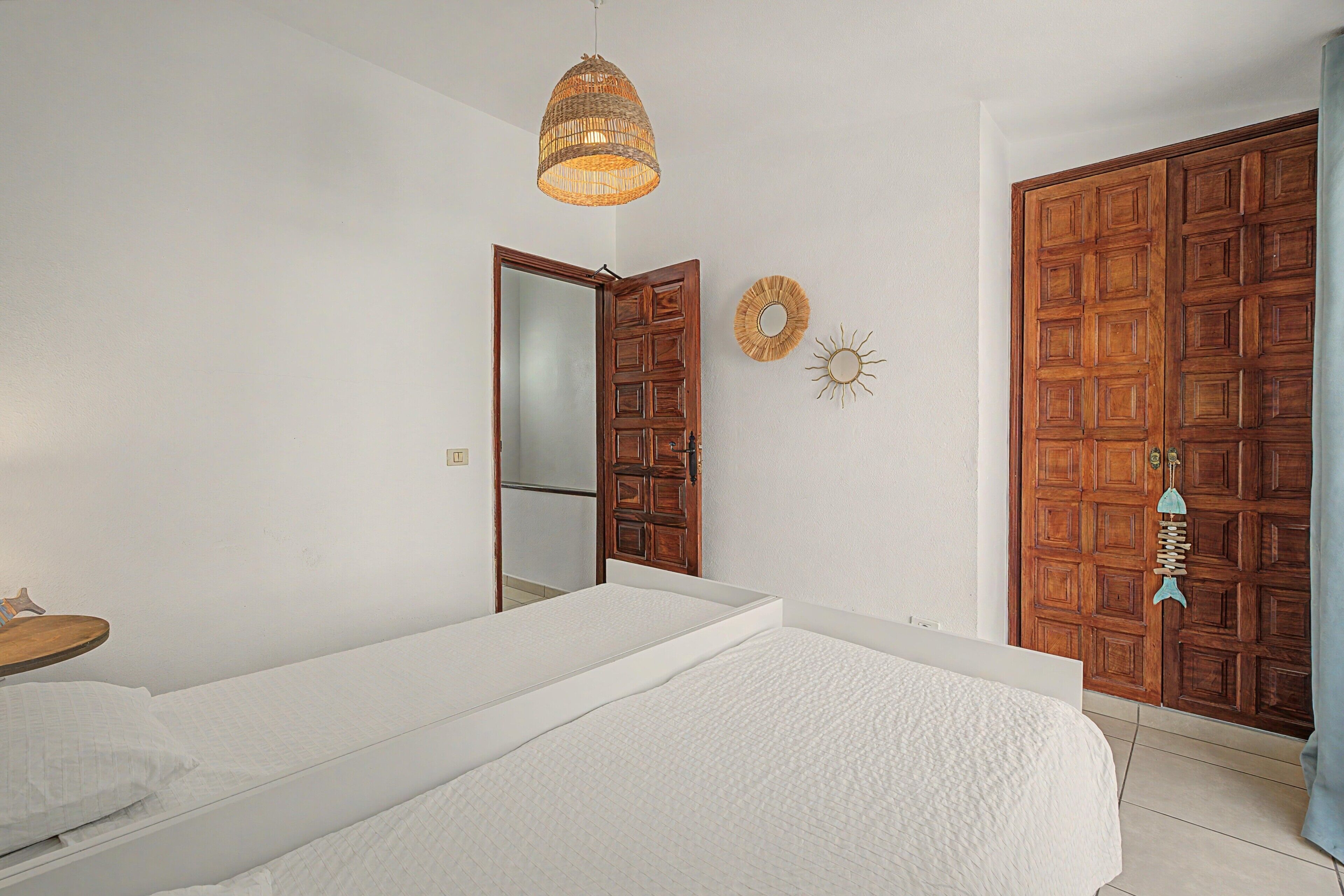 Une chambre à coucher comprenant un lit, un luminaire suspendu, une armoire et un miroir.