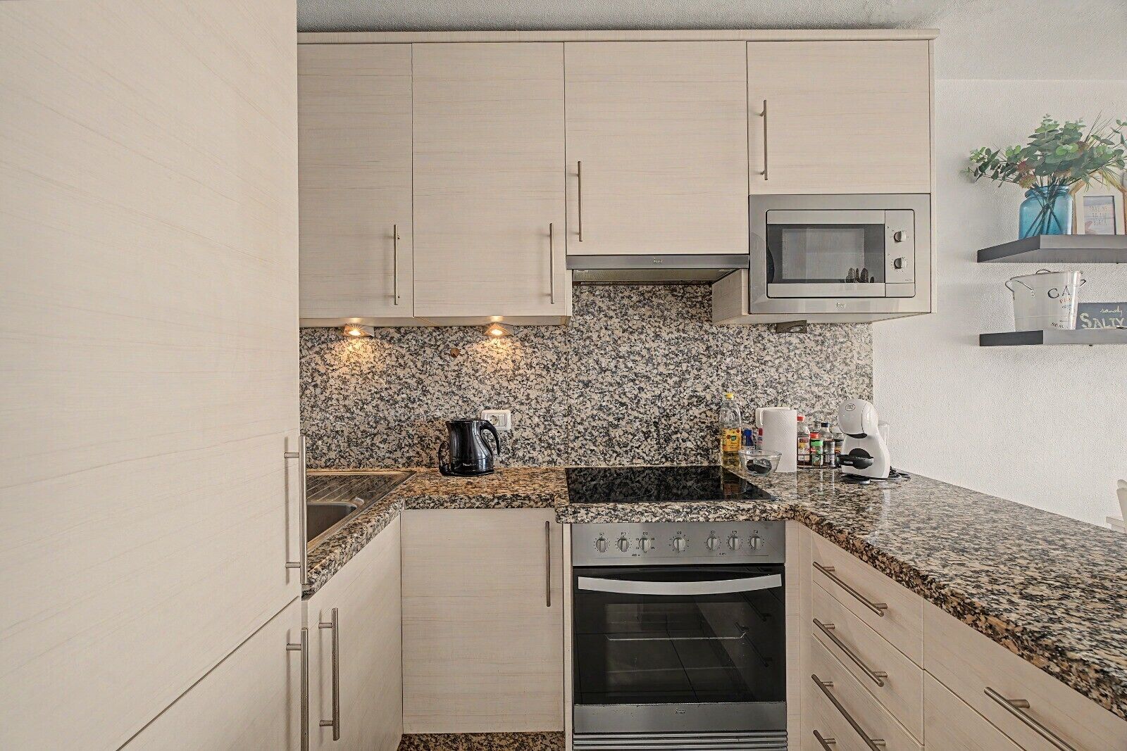 A modern kitchen with granite countertops, stainless steel appliances, and light wood cabinets.