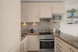Una cocina moderna con encimeras de granito, electrodomésticos de acero inoxidable y armarios de madera clara.