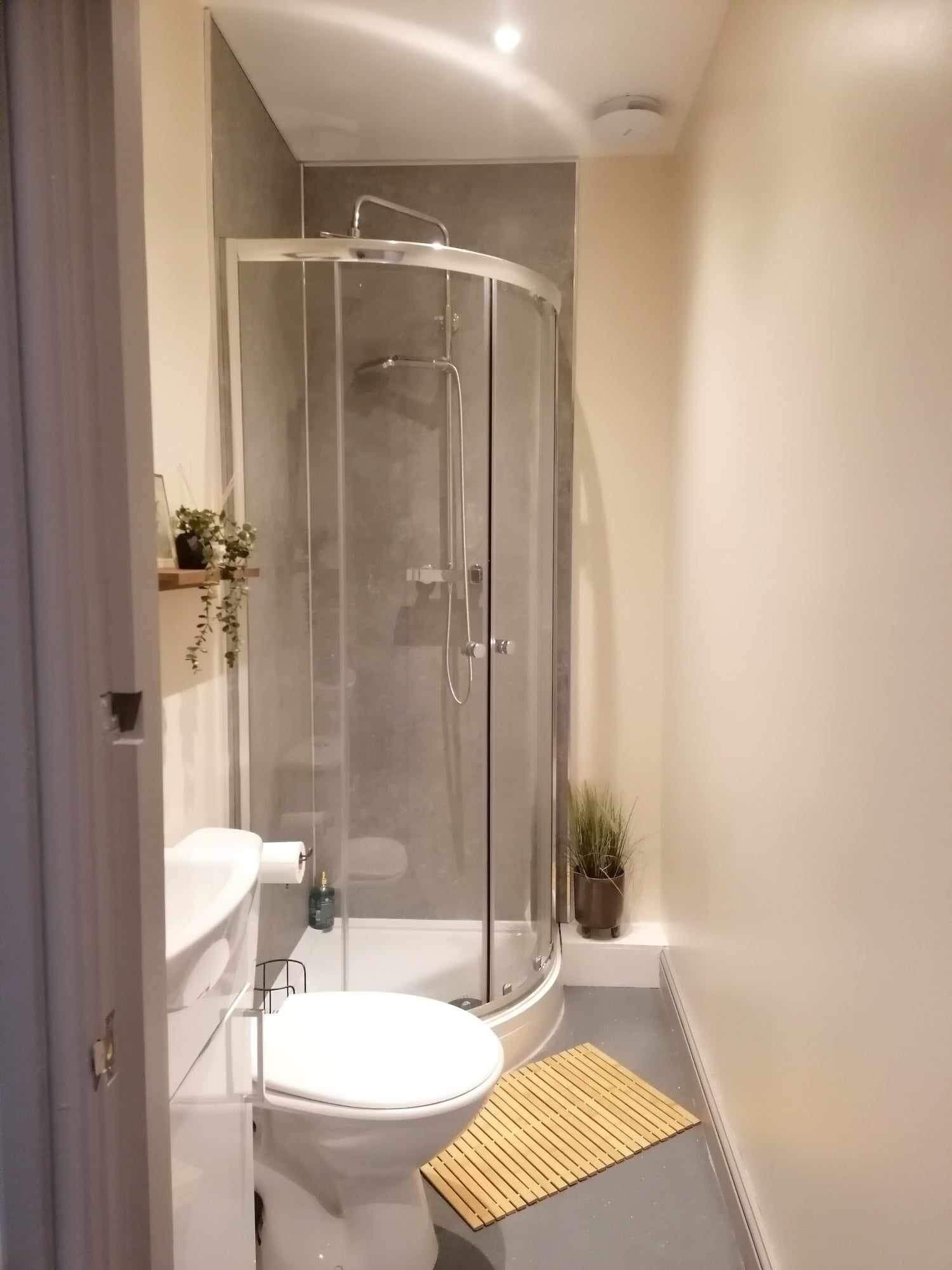 Une salle de bain moderne dotée d’une douche à parois de verre, de toilettes et d’un lavabo.