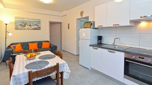 A compact kitchen with white cabinets, a built-in oven, and a microwave. - Holiday apartment with air conditioning (Fažana)