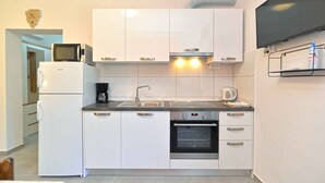 A compact kitchen with white cabinets, a built-in oven, a microwave, and a coffee maker. - Holiday apartment with air conditioning (Fažana)