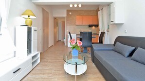 Un salon moderne avec une table basse en verre, un canapé gris et un téléviseur fixé au mur.