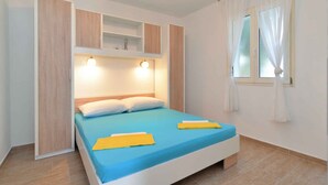Une chambre à coucher comprenant un lit, des étagères intégrées, une fenêtre avec des rideaux et un luminaire au-dessus du lit.