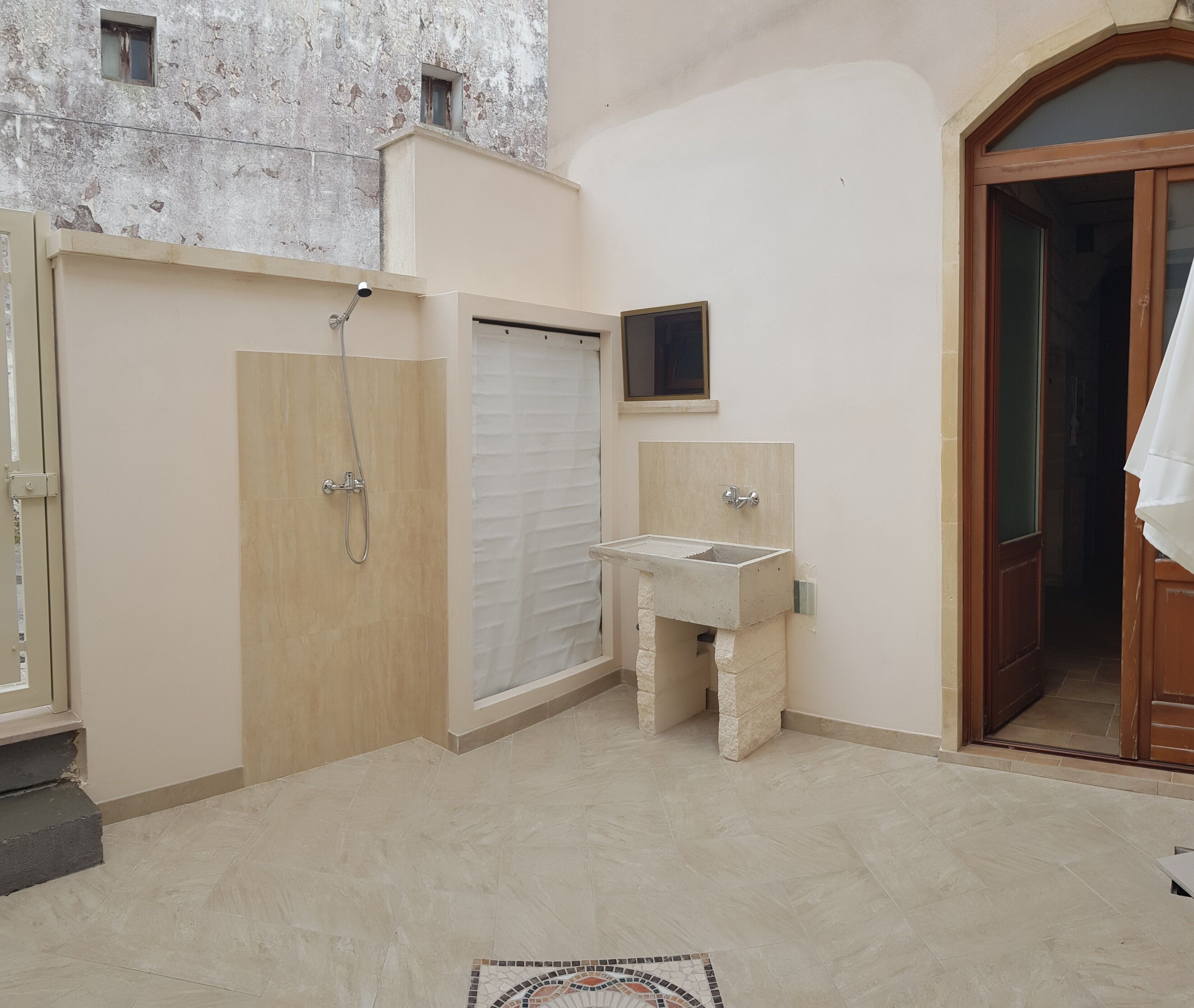 Une salle de bain avec une douche, un lavabo et une petite fenêtre.