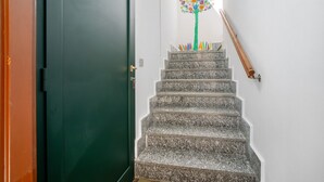Een trap met een leuning, een groene deur en een decoratieve boom aan de muur.