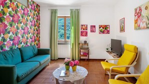 Een woonkamer met een bank, fauteuil en een tafel met bloemen.