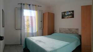 Um quarto com uma cama, uma janela com cortinas, um quadro na parede e armários de madeira.
