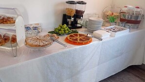 A buffet table with various food items, including pastries, a fruit bowl, and condiments.