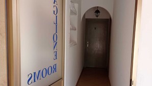A hallway with a door labeled 'ROOMS' and a welcome mat.