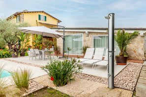 A patio with a pool, outdoor furniture, and potted plants.