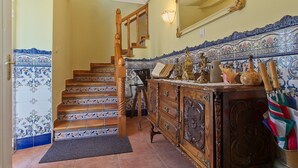 A staircase with ornate railings, a wooden cabinet with decorative items, and a tiled wall with a floral pattern.