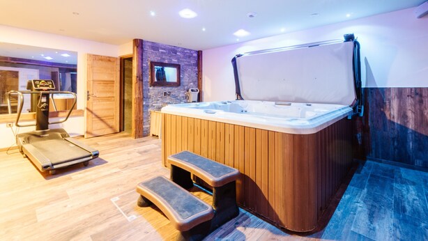 Un spa moderno con bañera de hidromasaje, cinta de correr y una pared de madera con espejo.