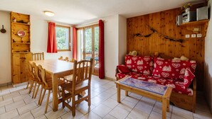 Un comedor con una mesa y sillas de madera, un sofá con cojines estampados y una pared de madera con estantes.