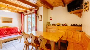 Ein Holzinterieur mit Esstisch, Stühlen, einer Couch und einem Fernseher.
