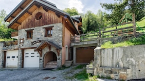 Eine rustikale Chalet mit Steinaußenseite, Holzbalkonen und einer Garage.