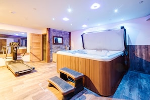 Un spa moderno con bañera de hidromasaje, cinta de correr y una pared de madera con espejo.