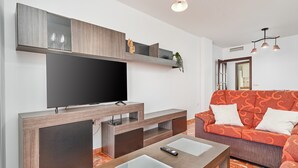 A modern living room with a flat-screen TV, a sofa, a coffee table, and a TV stand.