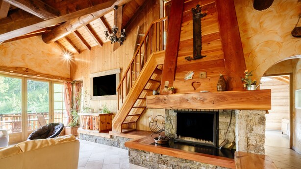 Un interior de madera con chimenea, una escalera y un sofá.