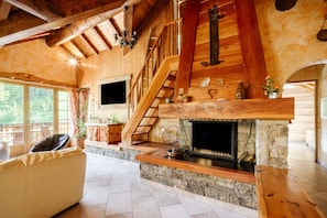 Un intérieur en bois avec une cheminée, un escalier et un canapé.