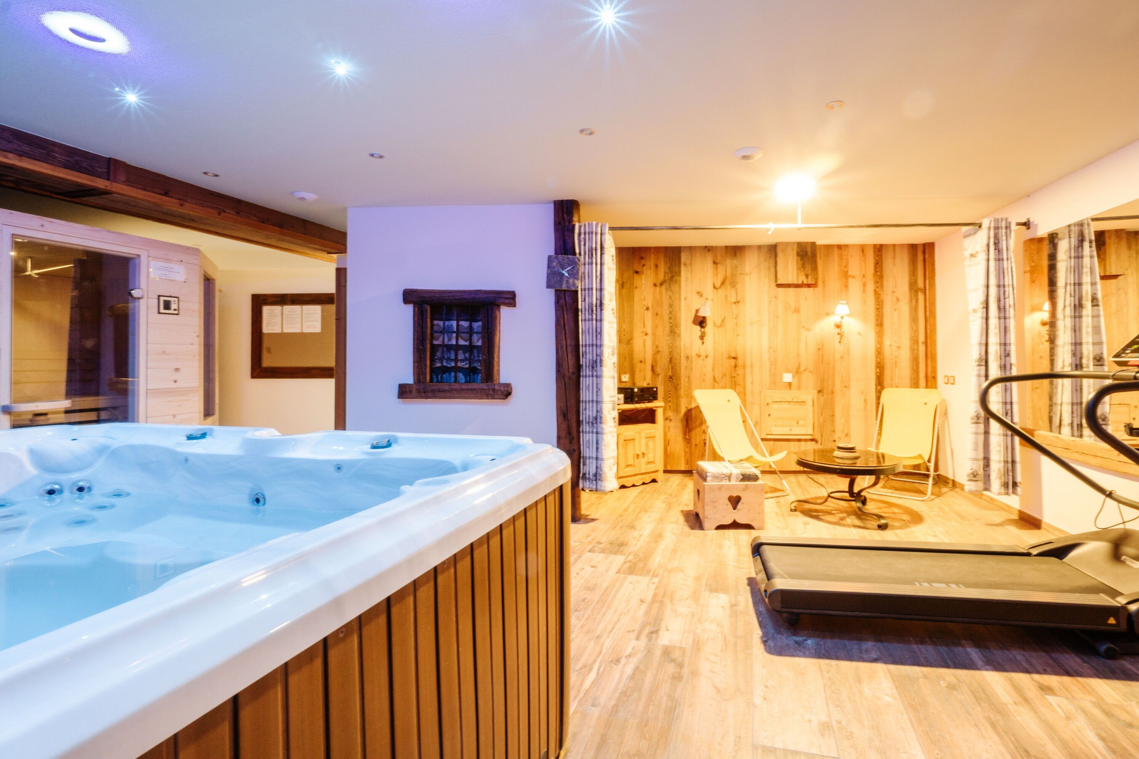 Ein Zimmer mit Whirlpool, Fitnessgeräten, Holzwänden und einem kleinen Fenster.