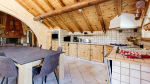 Una cocina rústica con vigas de madera, una mesa de comedor con sillas y un salpicadero de azulejos.
