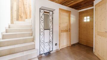 A staircase leading to a wooden door with a small window, a metal decorative element, and a tiled floor.