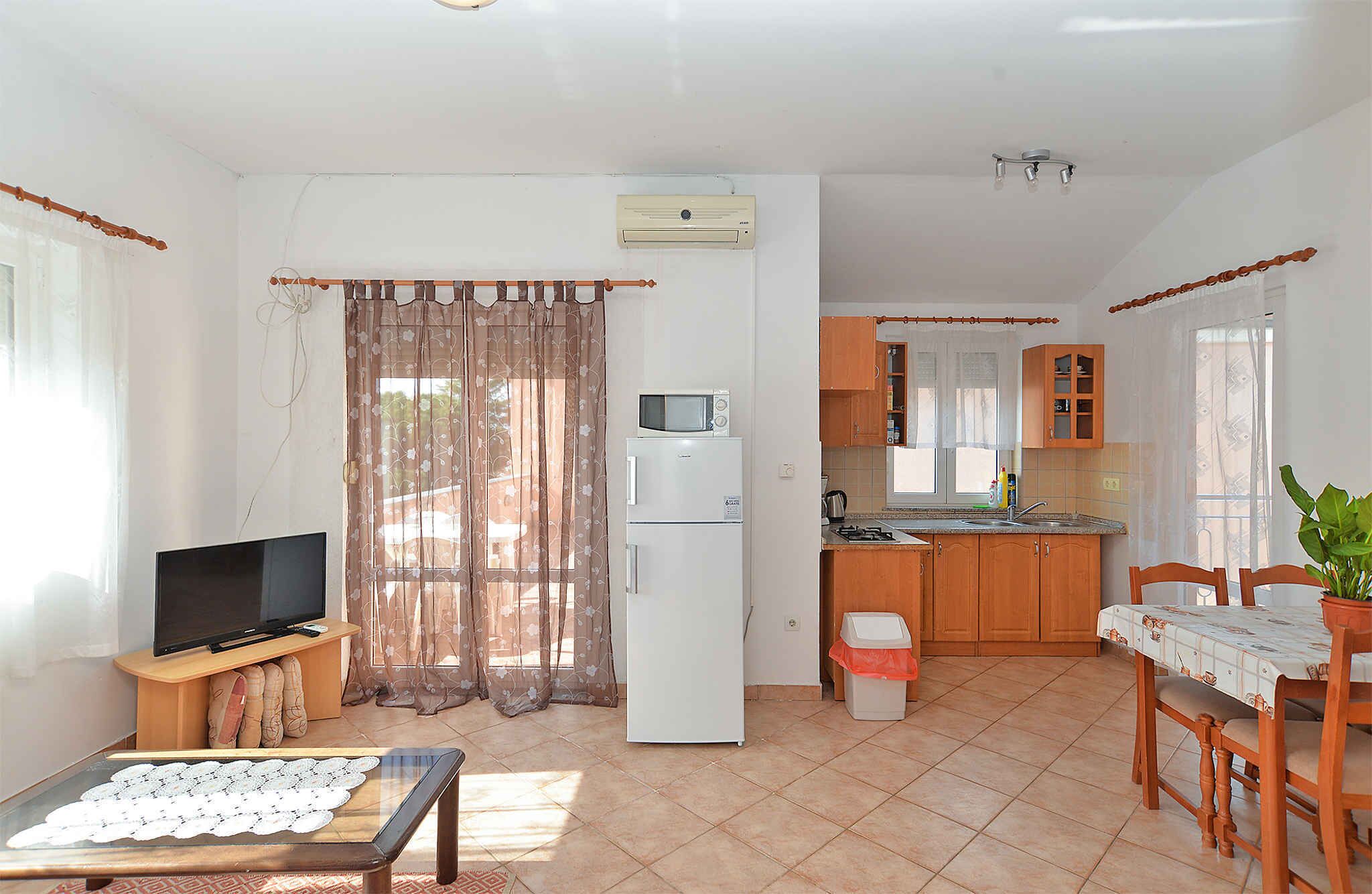 Un espace de vie compact comprenant une kitchenette, un coin repas et un téléviseur dans le salon.