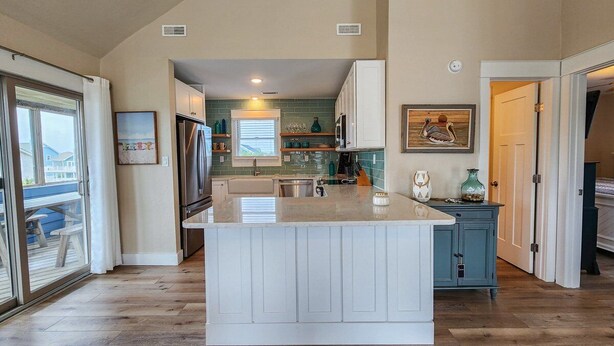 A spacious kitchen with a large island, white cabinetry, and a view to the outside. - SEA GLASS SHACK -  4 bed, 2 bath, Pool, Hot Tub & Dogs Allowed (Corolla)